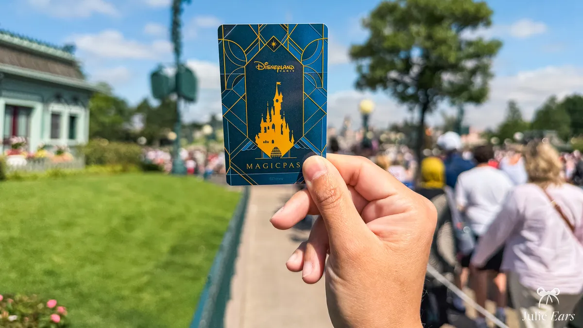 Hand holding a midnight blue and gold MagicPass card, the Disney hotels resort card that holds your meal vouchers, at Disneyland Paris