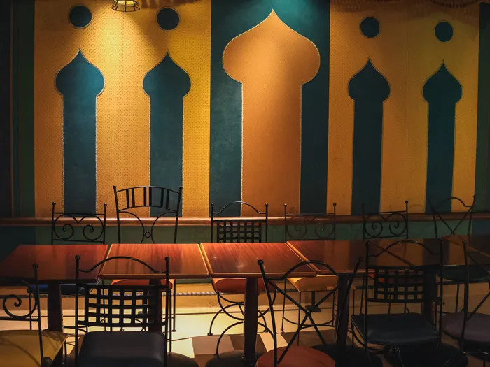 Mur aux arches orientales bleu et jaune surplombant tables et chaises en fer forgé de l’Agrabah Café