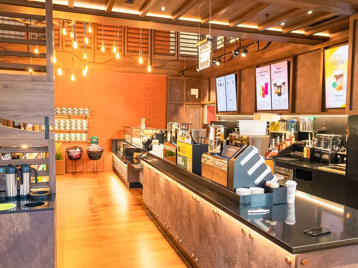Starbucks counter at Disney Hotel Cheyenne, Disneyland Paris: wood and metal bar, orange tiled wall, hanging bulbs and menu screens
