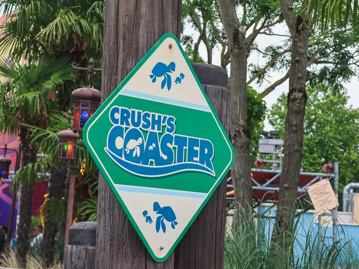 Panneau losange vert et bleu Crush’s Coaster fixé sur un poteau, de jour, à Worlds of Pixar