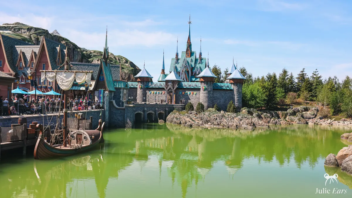 Arendelle castle and village houses of World of Frozen by the lake, with a moored sailing boat, at Disney Adventure World, Disneyland Paris
