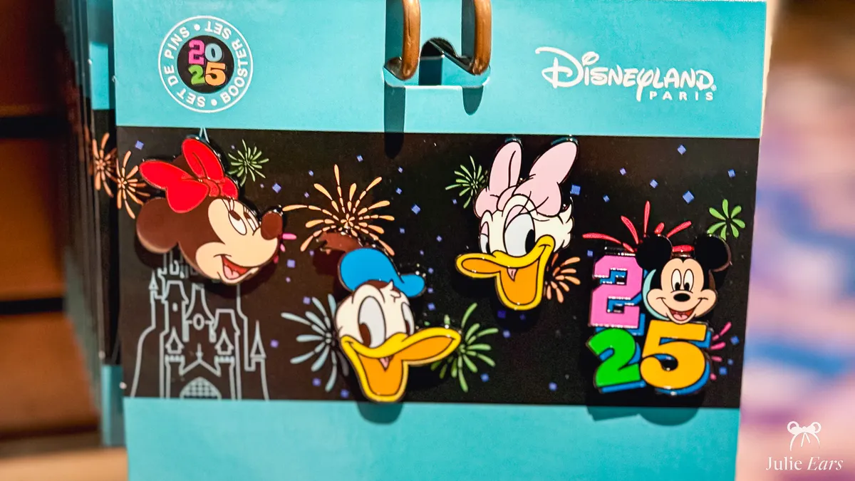 Set of four Disneyland Paris 2025 pins with Minnie, Donald, Daisy and Mickey, on a card decorated with fireworks and the castle