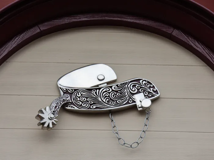 Éperon en métal ciselé fixé sous une arche sur la façade en bois du Silver Spur Steakhouse, restaurant de Frontierland.