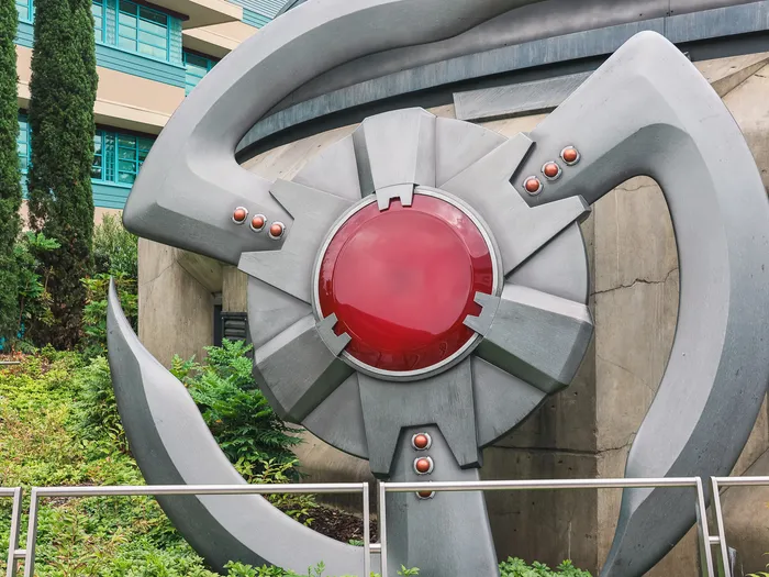 Grande sculpture métallique de l'emblème des Avengers, au dôme rouge, à Marvel Avengers Campus.