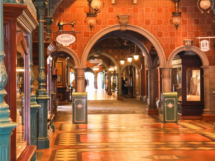 Galerie couverte de la Discovery Arcade avec arches, colonnes vertes et sol carrelé le long de Main Street USA.