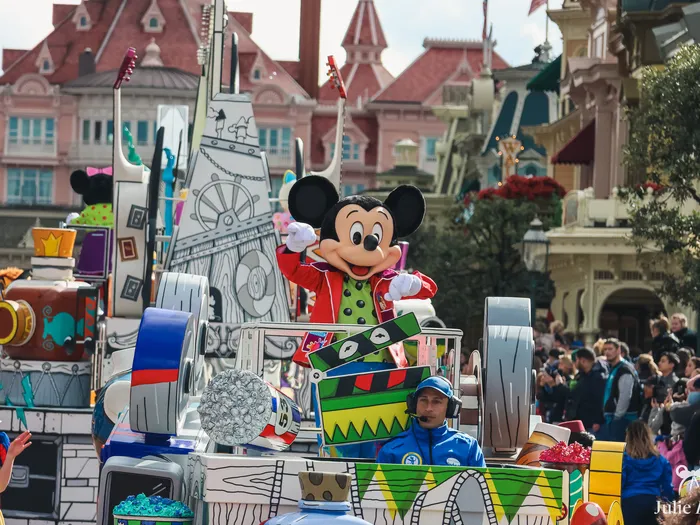 Mickey en veste rouge salue depuis son char musical de la parade A Million Splashes of Colour, décors de Main Street