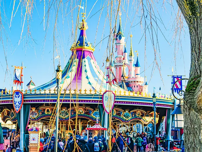Le Carrousel de Lancelot vu de face, parterres de fleurs roses au premier plan et château rose en arrière-plan.