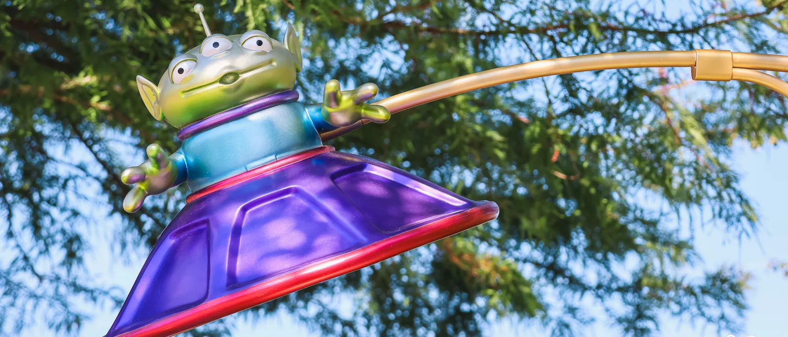 Figurine d’un Alien de Toy Story dans sa soucoupe violette, perchée devant les arbres au Parc Disney Adventure World.