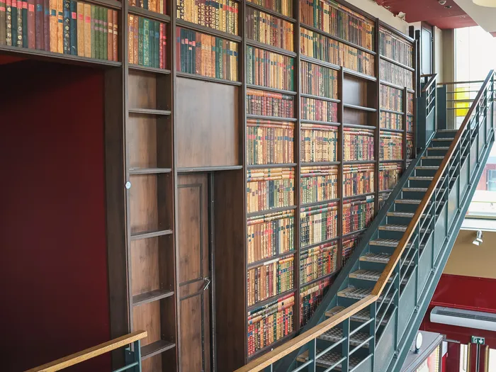 Mur de fausse bibliothèque et escalier métallique dans la salle d’Earl of Sandwich, à Disney Village.