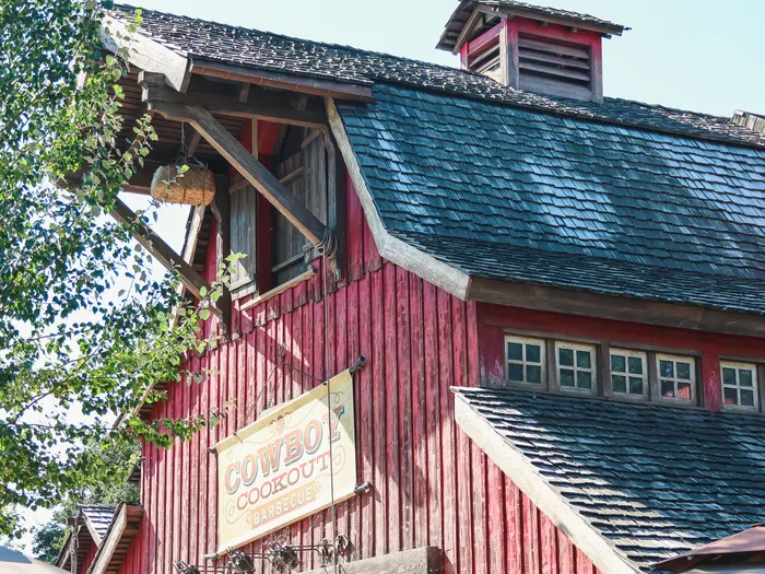 Grange western en bois rouge du Cowboy Cookout Barbecue et son enseigne peinte, à Frontierland.