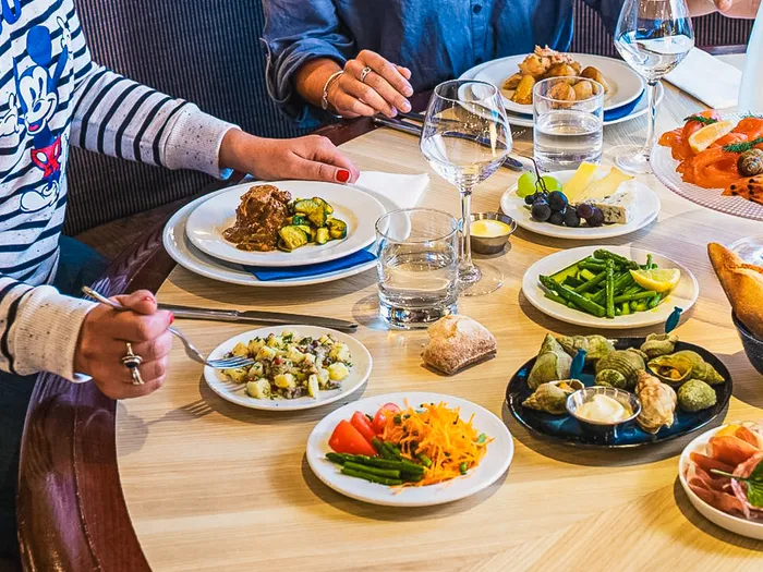 Table garnie de plats variés (viande, légumes, charcuterie, pain) au restaurant Cape Cod du Disney Newport Bay Club