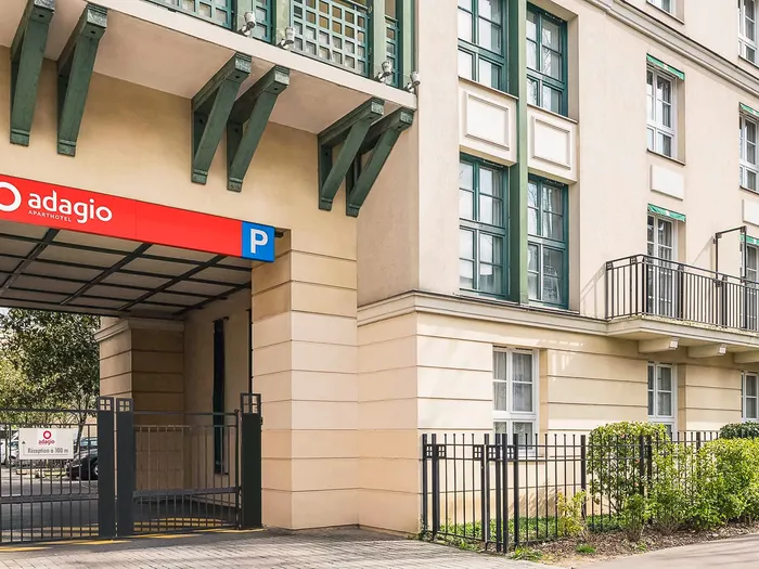 Entrée du parking couvert de l’Adagio Aparthotel signalée par une enseigne rouge