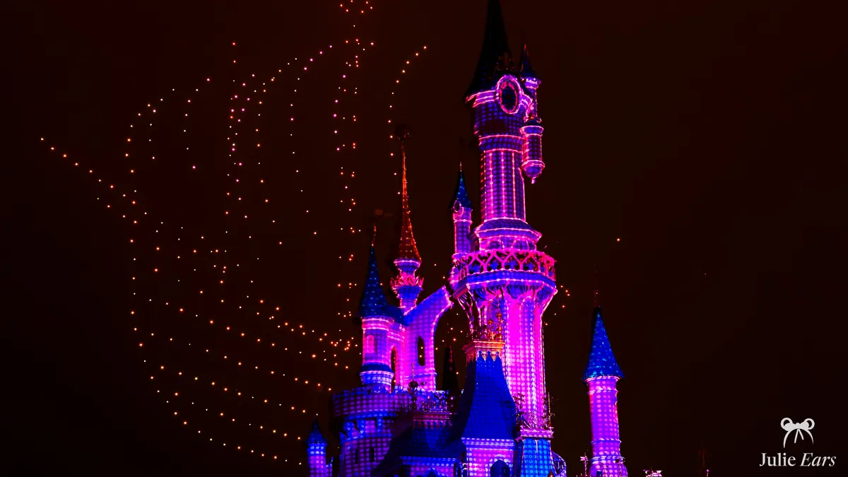 Orange drones forming a figure near Sleeping Beauty Castle lit in pink and blue, the Halloween 2024 drone show sequence at Disneyland Park