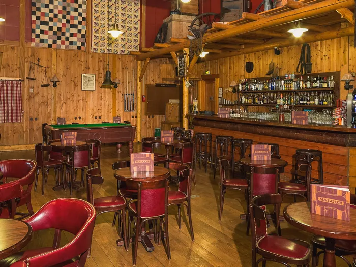 Salle du Crockett’s Saloon au décor western : murs en bois, fauteuils rouges, bar et billard