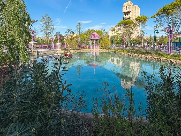 Plan d’eau de Raiponce Tangled Spin, kiosque rose et Tower of Terror visible au loin dans le Parc Disney Adventure World
