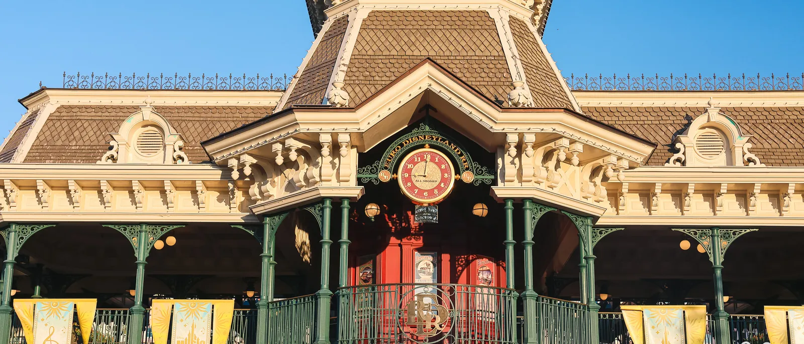 Façade de la gare de Main Street au Parc Disneyland, baignée de lumière dorée au petit matin, sans foule.