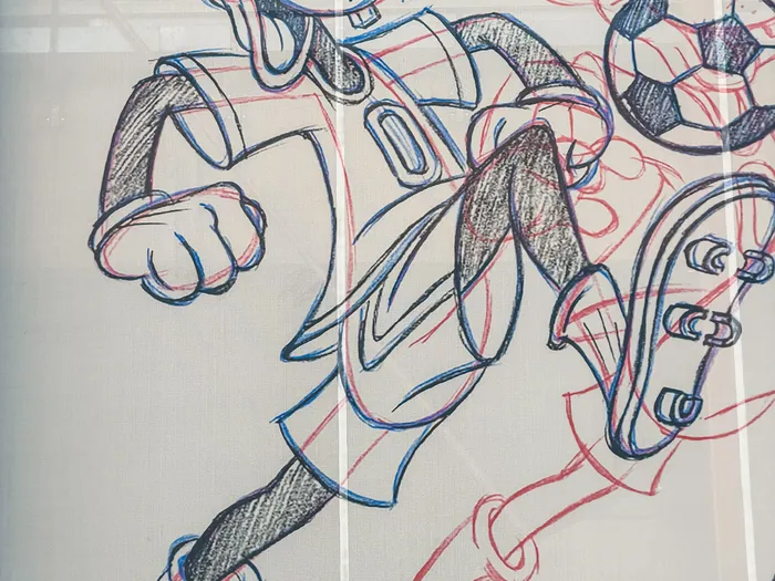 Croquis noir et rouge de Dingo courant après un ballon en crampons, décor mural du Sports Bar & Lounge à Disney Village.