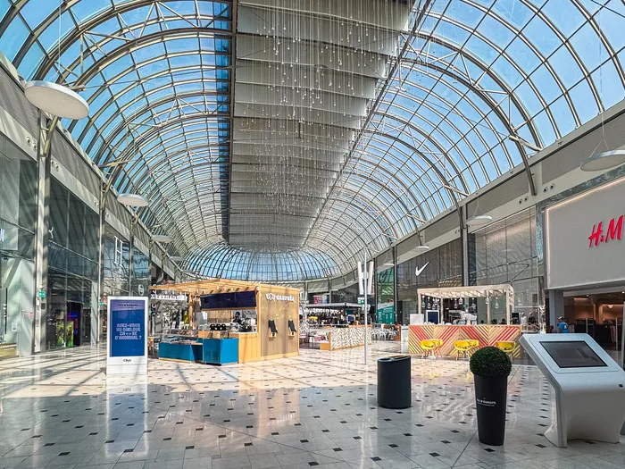 Walkway in the Val d’Europe shopping centre with its shop signs and glass roof, near Disneyland Paris