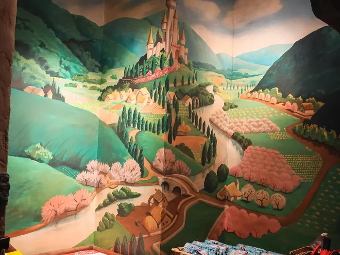 Mural of a hilltop castle above baskets of products, inside the shop