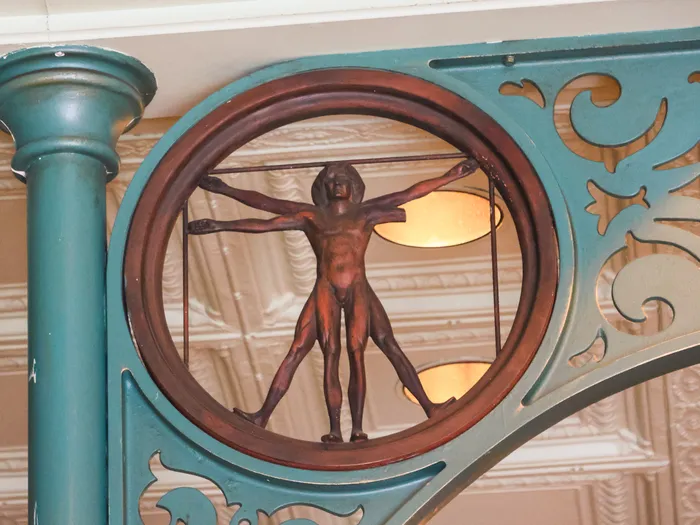 Figure de l’Homme de Vitruve encadrée dans la ferronnerie verte et cuivrée de la Discovery Arcade