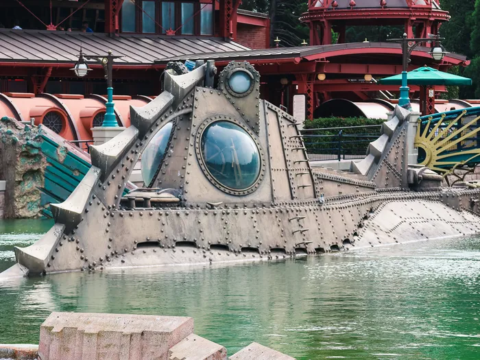 Le sous-marin Nautilus rivé émergeant de l'eau verte devant le décor de Discoveryland.