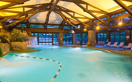La piscine intérieure du Disney Sequoia Lodge, décor de rondins avec cascade et toboggan