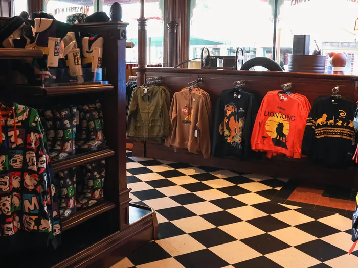 Disney-print clothes and "Lion King" T-shirts on the wood panelling above the chequered floor of Main Street Motors at Disneyland Paris