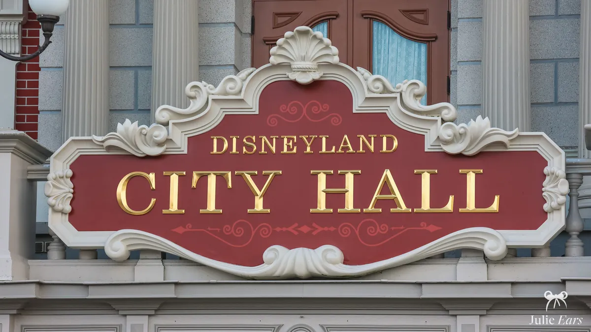 Disneyland City Hall sign with gold letters on a red background, on the City Hall facade at Disneyland Paris.