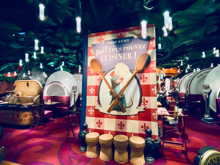 Salle du Bistrot Chez Rémy avec décor surdimensionné Ratatouille, assiettes géantes, bouchons de champagne et enseigne de Rémy