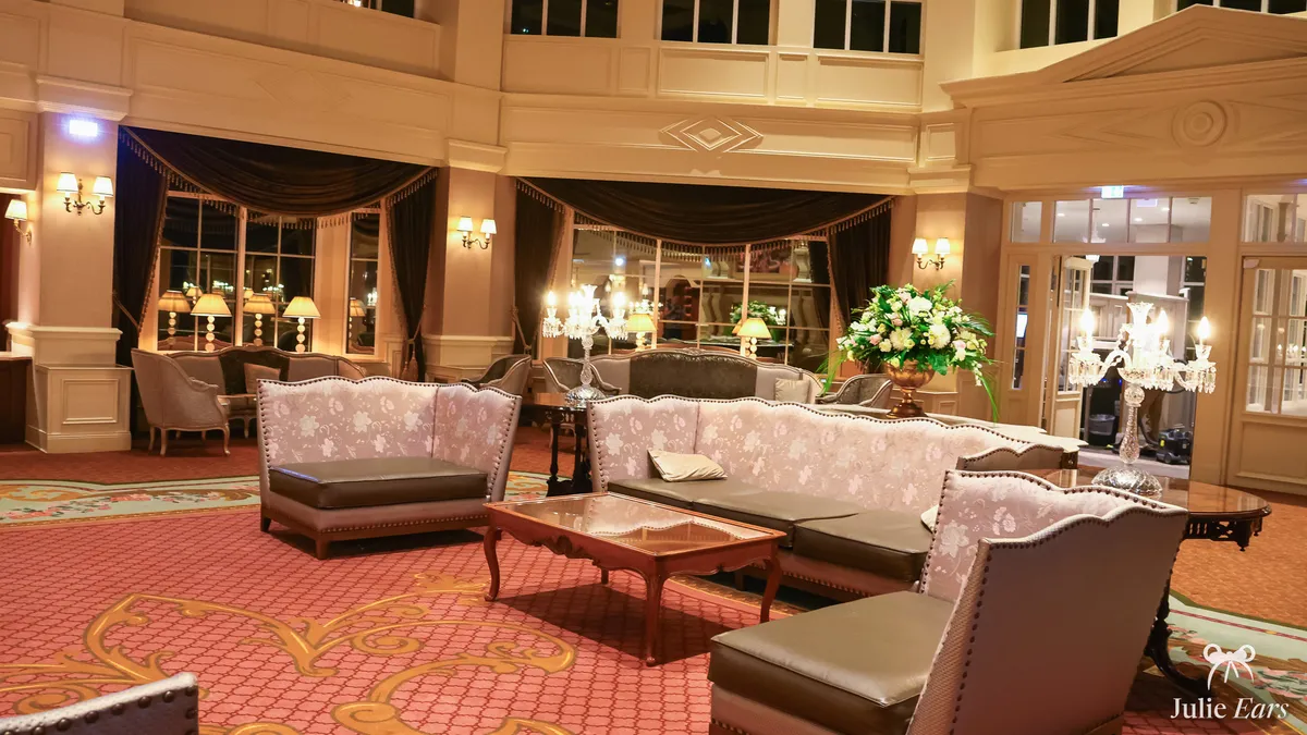 Disneyland Hotel lobby lounge at Disneyland Paris: floral sofas, a wooden coffee table, crystal candelabras, white and pink flowers and coral carpet