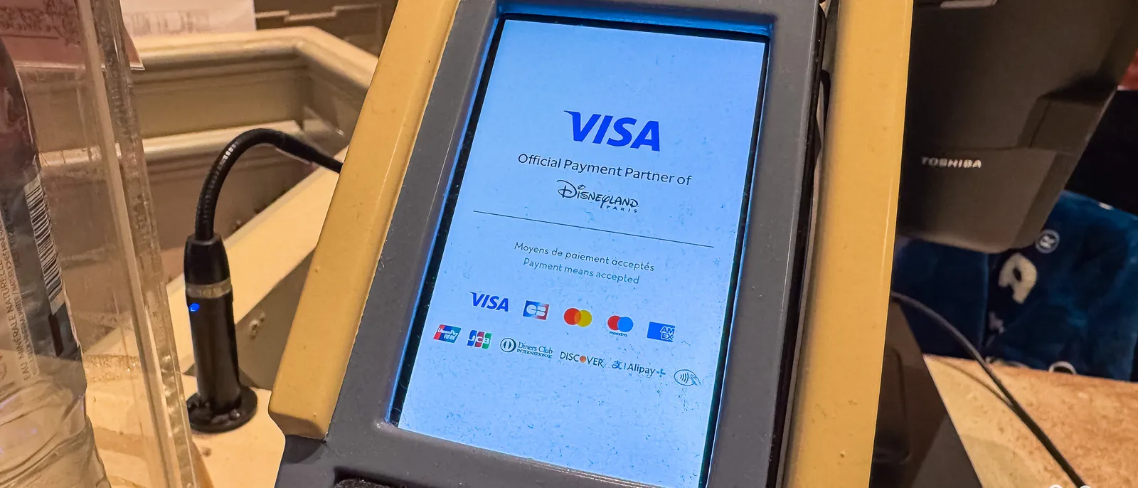 Terminal de paiement affichant l’écran Visa, partenaire officiel de Disneyland Paris, avec les moyens de paiement acceptés.