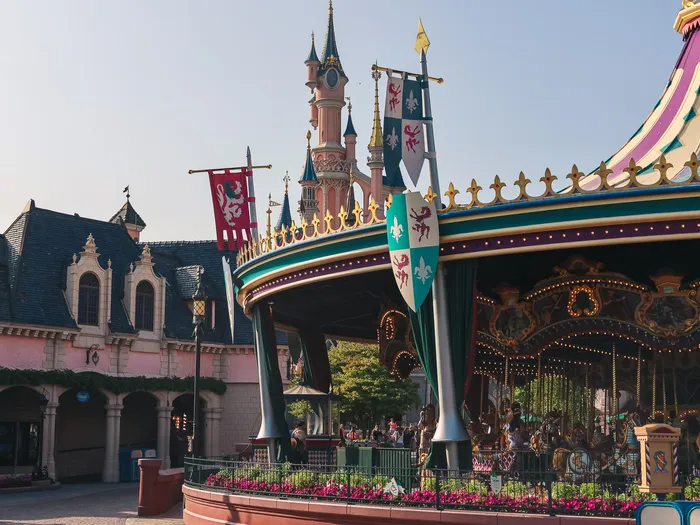 Carrousel médiéval aux bannières colorées devant le château de la Belle au Bois Dormant, à Disneyland Paris.