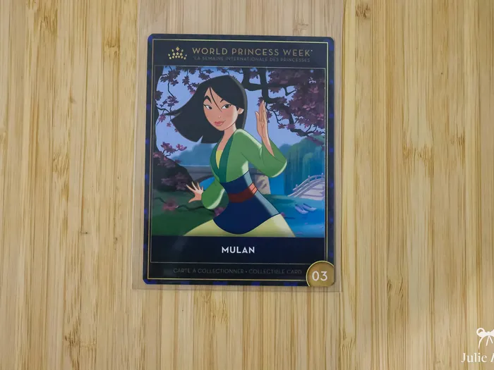 Carte à collectionner Mulan de World Princess Week posée sur une surface en bois