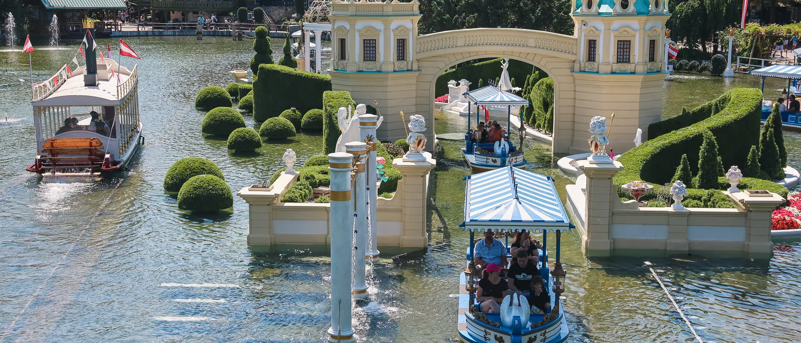 Barques glissant sur l’eau devant des pavillons baroques et des jardins taillés à Europa-Park.