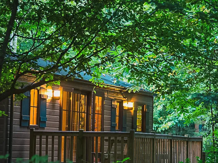Bungalow en bois aux fenêtres éclairées du Disney Davy Crockett Ranch, niché dans la forêt à Disneyland Paris.