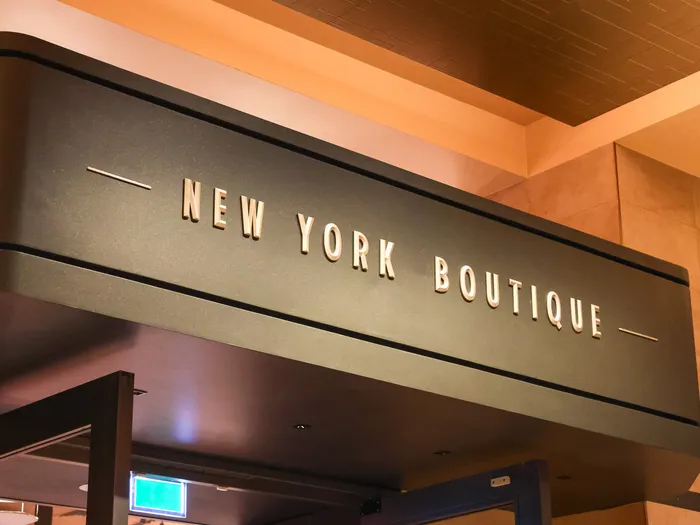 Gold New York Boutique sign on a dark band, with the hotel’s Art Deco ceiling