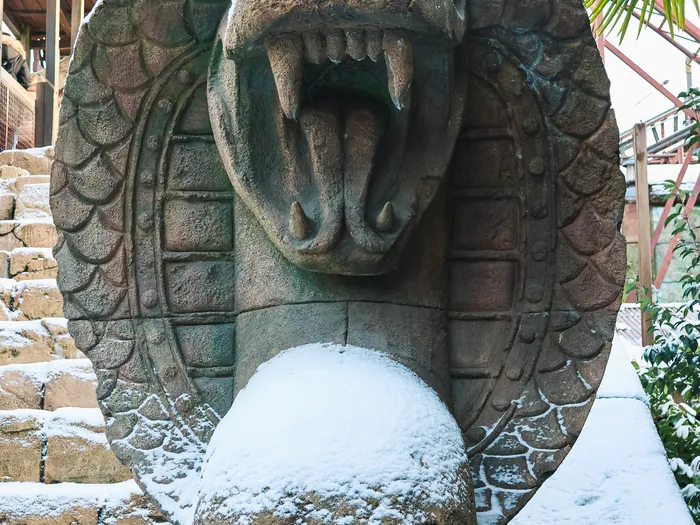 Grande statue de cobra gueule ouverte au pied d’un escalier enneigé, décor d’Indiana Jones and the Temple of Peril.