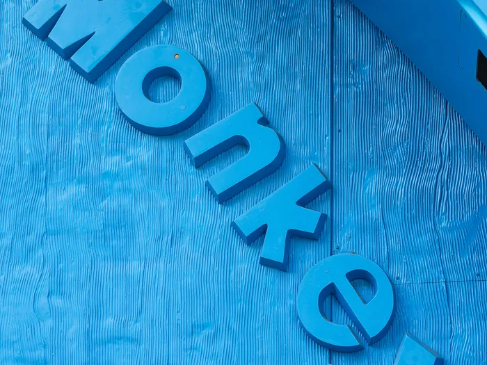 Raised blue letters spelling the word Monkeys, fixed to the blue-painted wooden wall of the Toy Story Playland shop at Disneyland Paris.