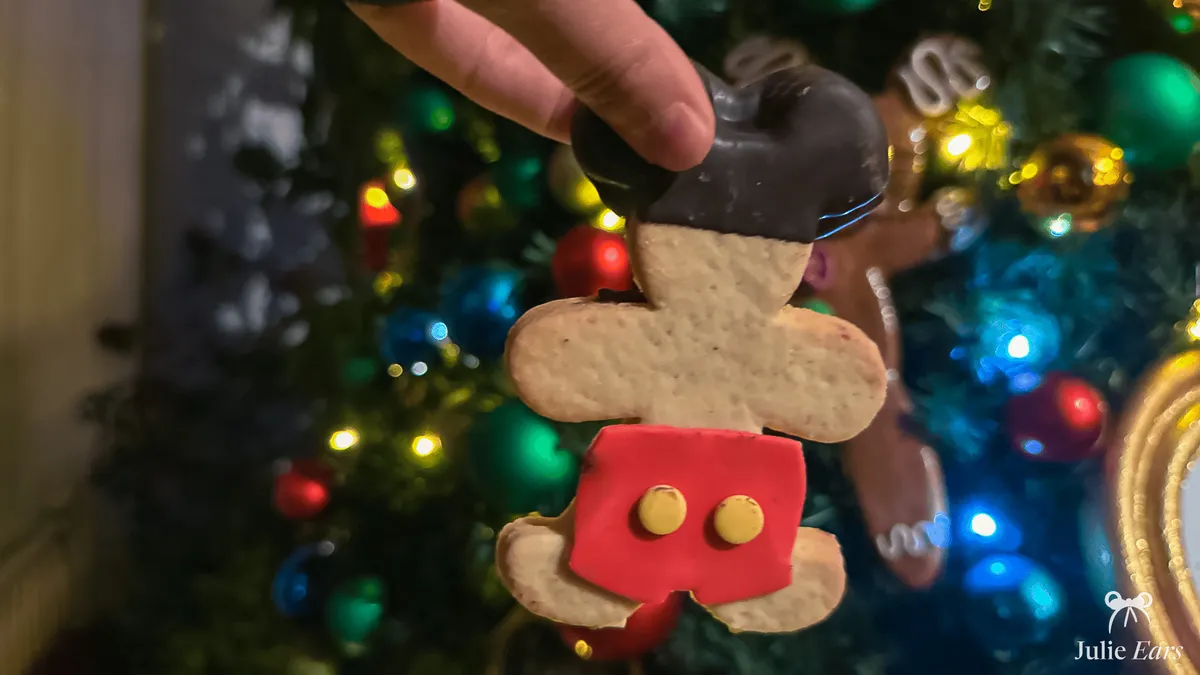 Sablé décoré en forme de Mickey (tête chocolatée et short rouge à boutons) devant un sapin de Noël à Disneyland Paris