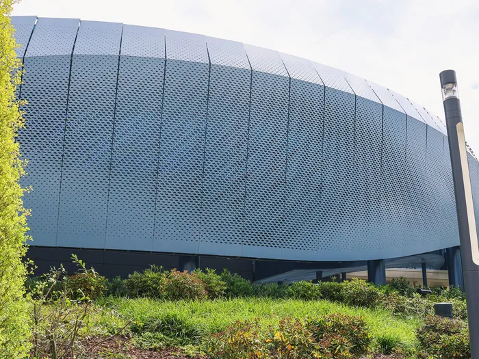 Façade métallique bombée du bâtiment de l’attraction Avengers Flight Force, bordée de végétation à Avengers Campus.