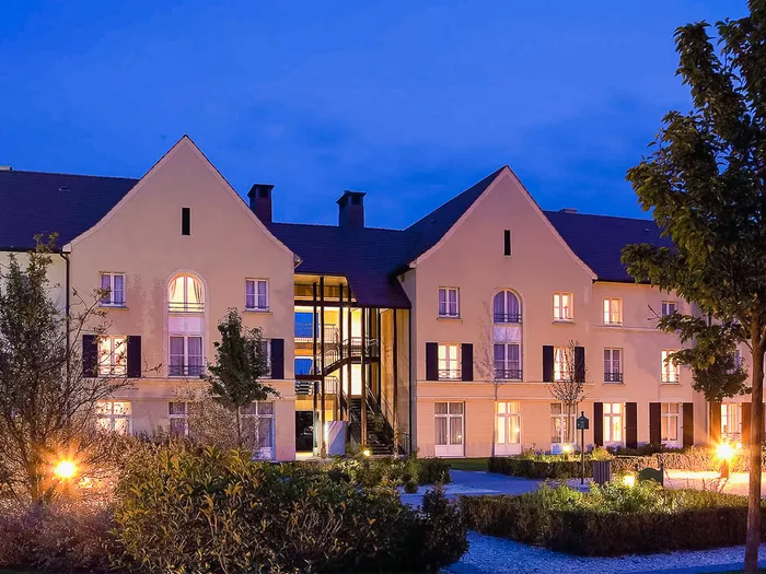 Façade de l’hôtel Campanile près de Disneyland Paris illuminée au crépuscule, jardins au premier plan