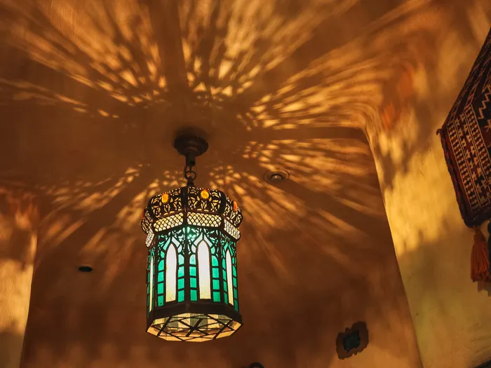 Lanterne orientale en verre vert projetant des motifs de lumière au plafond du Passage Enchanté d’Aladdin.