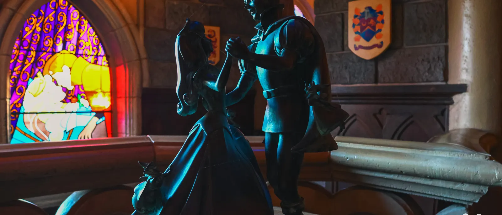 Statue sombre du prince Philippe dansant avec Aurore devant un vitrail coloré, galerie du château, Disneyland Paris