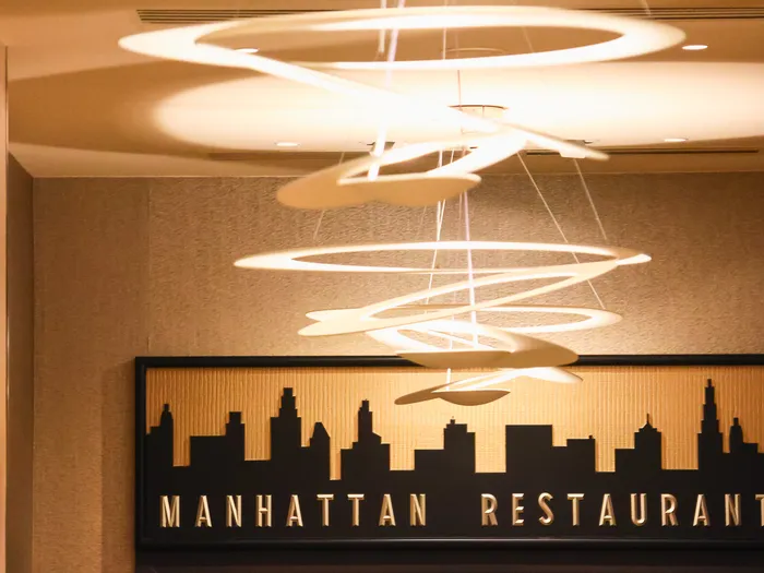 Fresque de la skyline de Manhattan et suspensions spiralées éclairant l’enseigne du Manhattan Restaurant