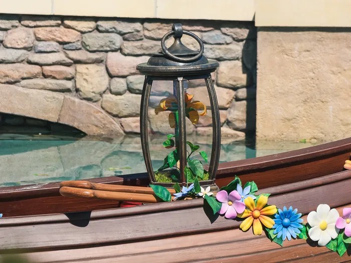 Barque en bois ornée de fleurs et d’une lanterne sur l’eau, décor Raiponce d’Adventure Way.