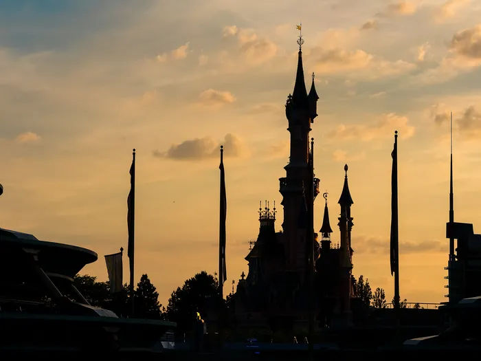 silhouette du château de la Belle au Bois Dormant et des mâts au coucher du soleil, Parc Disneyland.