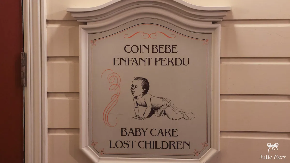 Bilingual Baby Care and Lost Children plaque with a drawing of a crawling baby, at the Baby Care Centre of Disneyland Park