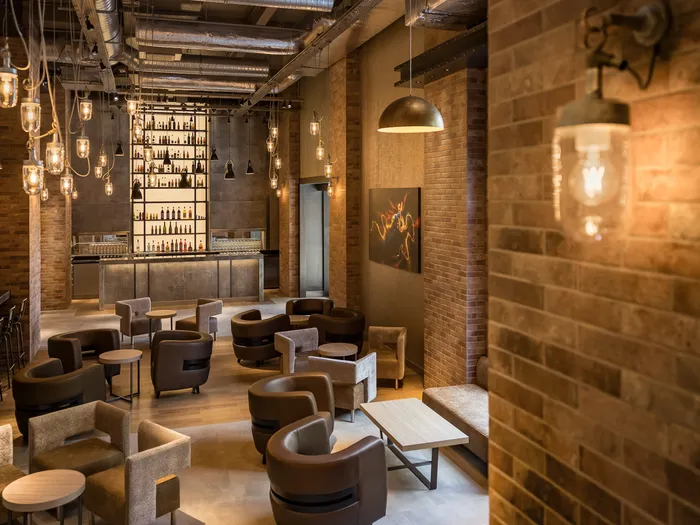 Salle du Bleecker Street Lounge au décor industriel : murs de briques, fauteuils en cuir et suspensions, au Disney Hotel New York