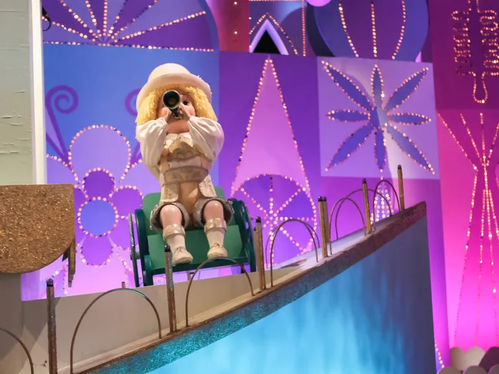 Automate poupée jouant de la trompette sur un décor bleu et violet d’it’s a small world