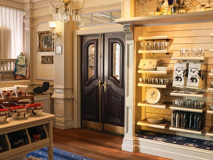 Dark wooden doors framed by shelves of patterned glasses, plates and mugs, at Lilly’s Boutique, at Disneyland Paris.
